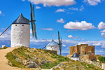 Wind mills and old castle in Consuegra, Toledo, Castilla La Mancha, Spain. Picturesque landscape with view to ancient walls and windmills on blue sky with clouds.