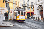 Lisbon, Portugal. Vintage yellow retro tram on narrow bystreet tramline in Alfama district of old town. Popular touristic attraction of Lisboa city.