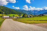Austria country road among picturesque landscapes and villages in austrian Alps mountains. Blue sky with clouds. Green lawns between forests.