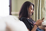 Tween girl texting with smart phone on sofa