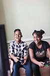 Happy tween girl friends playing video game in living room