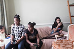 Tween girl friends playing video game on living room sofa