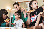 Lesbian couple and daughters eating pizza