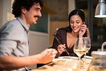 Happy couple eating dinner with chopsticks and drinking white wine