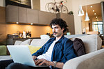 Man using laptop on living room sofa