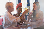 Happy, carefree young women friends toasting cocktail glasses in bar