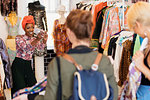 Young woman with camera phone photographing friends shopping in clothing store