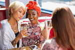 Young women friends drinking cocktails, posing for photograph in restaurant