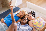 Young women friends using instant camera on bed