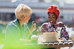 Young women friends enjoying dim sum lunch at sunny sidewalk cafe