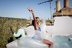 Portrait playful, confident young woman sitting on inflatable pegasus in sunny rooftop hot tub