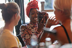 Young woman photographing friend with digital camera in cafe