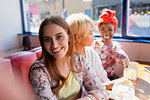 Portrait smiling young woman in sunny restaurant with friends