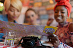 Young women friends looking at map on vacation in restaurant