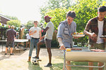 Male friends enjoying barbecue in sunny summer backyard