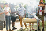 Male friends drinking beer and barbecuing in sunny summer backyard