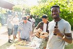 Portrait confident young man drinking beer, enjoying barbecue in summer backyard