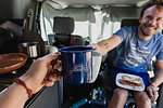 Personal perspective couple toasting coffee cups in camper van