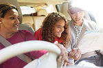 Family with map riding in car on road trip