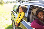 Carefree girl leaning out window of car