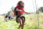 Happy girl with backpack camping, running in sunny field
