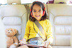 Portrait smiling, confident girl watching movie with headphones and digital tablet in back seat of car