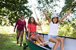 Happy mother and daughters pushing canoe in woods