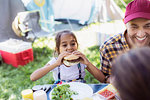 Father and daughter eating barbecue hamburgers at campsite