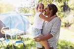 Portrait affectionate mother and daughter hugging at sunny campsite