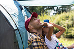 Curious father and daughter bird watching with binoculars at sunny campsite