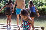Family playing, jumping off dock into sunny river