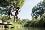 Carefree mother and daughter jumping into river