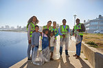 Portrait happy volunteers picking up litter on sunny boardwalk