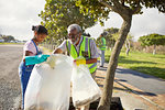 Grandfather and granddaughter volunteers cleaning up litter in sunny park