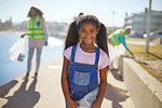 Portrait smiling girl volunteer cleaning up litter on sunny boardwalk