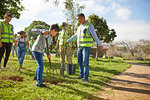 Multi-generation family volunteers planting trees in sunny park