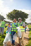 Portrait happy multi-generation men volunteering, cleaning up litter in sunny park