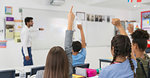 Junior high school students with hands raised during lesson in classroom