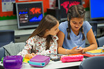 Junior high school girl students using smart phone at desk in classroom
