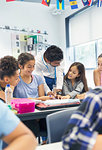 Teacher helping junior high school students at desk in classroom