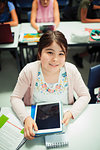 Portrait smiling, confident junior high school girl student using digital tablet in classroom