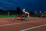 Teenage paraplegic athlete speeding along sports track in wheelchair race