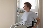 Thoughtful young woman in wheelchair at home
