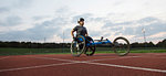 Determined young female paraplegic athlete training for wheelchair race on sports track