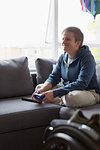 Smiling young woman playing video game on sofa