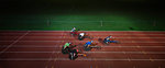 Paraplegic athletes racing along sports track in wheelchair race in night