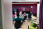 Male conductor leading women singing in music recording studio