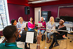 Womens choir with sheet music singing in music recording studio