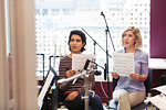 Women with sheet music singing in music recording studio