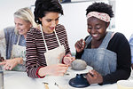 Women shaping clay in art class